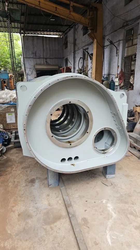 End view of the fabricated steel housing on workshop stands, showing a large flanged bore opening, a smaller bore and the bolted perimeter flange