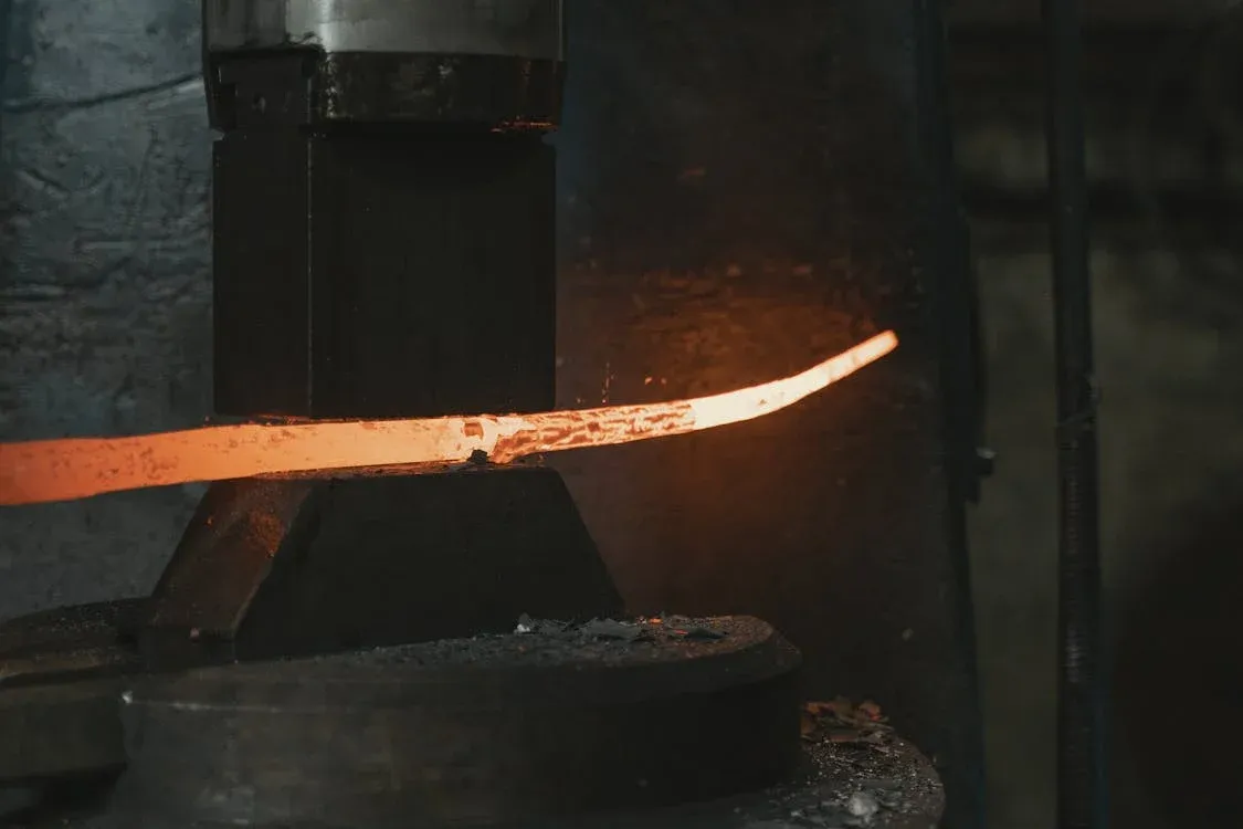 Glowing forged steel workpiece being shaped at an Anaya Enterprises forging facility